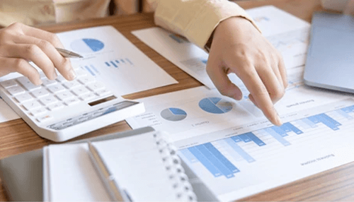 Analyzing the financial conditions Financial planning documents and calculator on a desk as a person analyzes costs for first-time homebuyers.