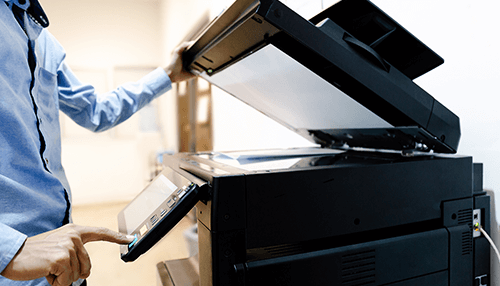 Ease of use A person operating a multifunction printer with scanning capabilities in an office environment.