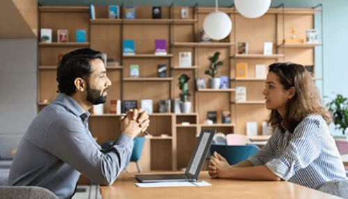 Employ stock images Two professionals having a one-on-one discussion in a modern workspace, possibly brainstorming new ideas for print marketing campaigns.