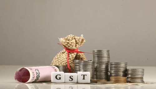 Late filing of gst return Stacks of coins, a money bag, and'GST' blocks, symbolizing GSTR and tax-related financial transactions.