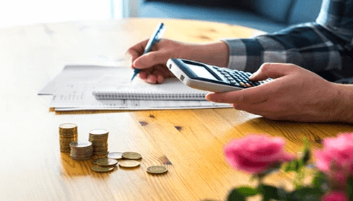 No income taxes - tycoonstory | tycoonstory media A person calculating finances at a table with coins and documents, symbolizing financial planning and tax advantages associated with wyoming llc benefits.