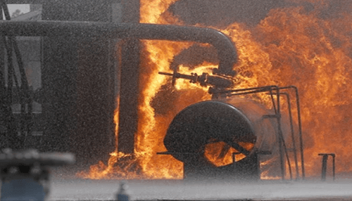 Oil field accidents Oil field industrial facility engulfed in flames during a refinery fire incident with large pipelines and processing equipment visible.