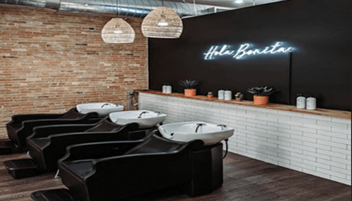 Salon Stylish salon hair washing station with black chairs, brick wall, neon sign and hanging lights.
