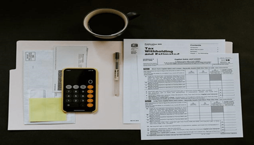 Wave Office desk setup with tax documents, calculator, pen, and envelopes, symbolizing financial planning and compliance challenges faced by startups.