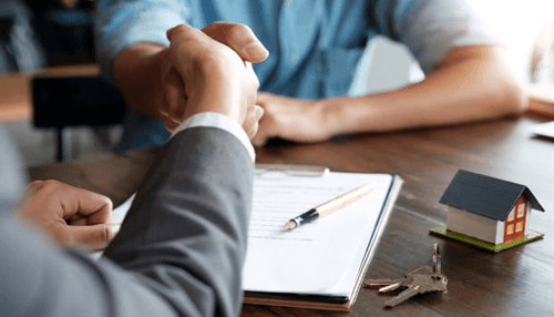 Working with a real estate company Real estate agent shaking hands with client during a property deal, symbolizing support for first-time homebuyers.