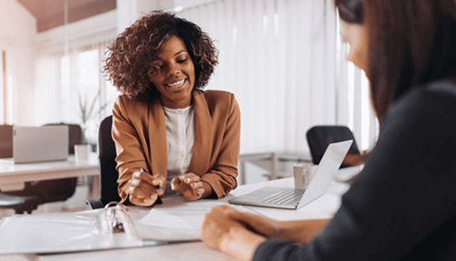 Customer comes first - tycoonstory | tycoonstory media Business women talking about plans in launching a business in the office, with documents and laptop on the table.
