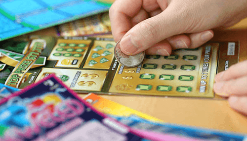 Playing the lotto A hand scratching off numbers on a lotto ticket, revealing potential winnings, capturing the thrill of living while playing the lotto