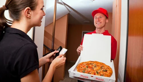 Pizza Delivery Smiling delivery person handing a pizza box to a customer at the doorstep, symbolizing fast food delivery service.