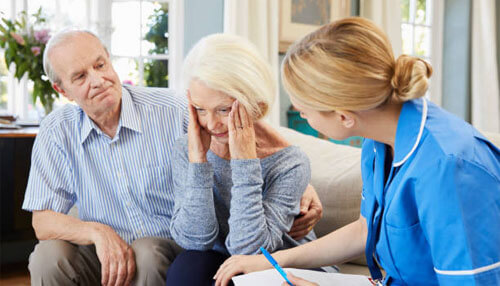 Psychiatric mental health nurse A healthcare professional in a blue uniform provides emotional support and consultation to an elderly couple in their home, highlighting the vital role of community nursing.