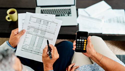 Invoice - tycoonstory | tycoonstory media Two people going over financial documents with a calculator and laptop, with a highlighted invoice template for precision.