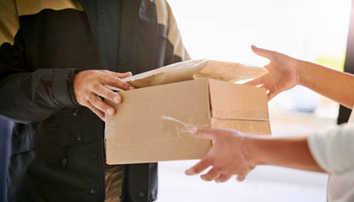 Delivery person handing over a package, illustrating distribution and supply chain services as part of various types of business services A person handing over a package to another, representing logistics and delivery services as part of various business service offerings.