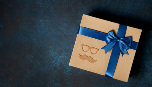 For the sporty dad - tycoonstory (1) | tycoonstory media Creative gift box wrapped with blue ribbon, featuring a unique design of glasses and a mustache, symbolizing fun and thoughtful gift ideas for special occasions.
