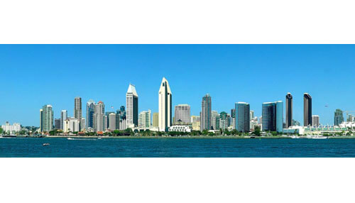 Los angeles Jason hughes overlooking a panoramic city skyline with modern skyscrapers along a waterfront under a clear blue sky.