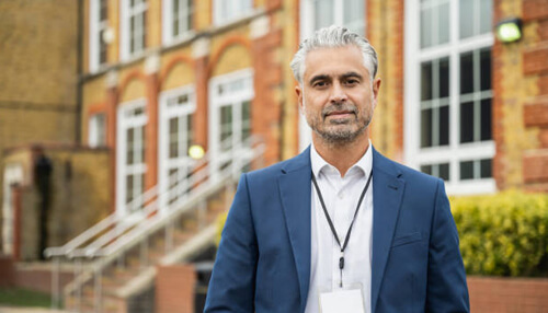 Teaching Teaching leader and school principal standing outside an academic building, representing educational leadership, guidance, and professional teaching environment.