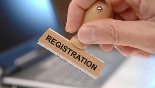 Gst registration Hand holding a wooden stamp labeled registration, symbolizing approval and document processing for gst registration.
