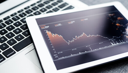 Tablet displaying financial chart analysis next to a laptop, symbolizing financial risk assessment and shipping insurance in crowdfunding. Financial risks shipping insurance