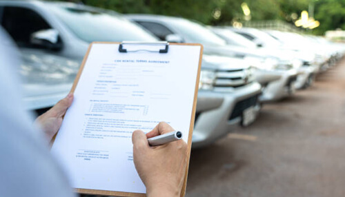 Get accurate vehicle data - tycoonstory | tycoonstory media A fleet manager with a clipboard inspecting parked vehicles, showcasing the role of effective fleet maintenance strategies.
