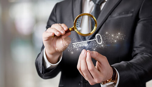 Businessman holding a magnifying glass and key representing keyword research and seo strategies. Know your google key keywords
