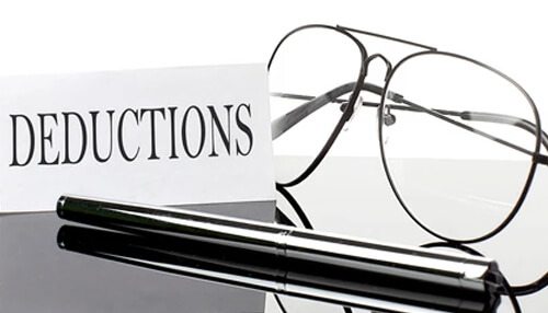 Optimize your deductibles A close-up image of a pair of eyeglasses and a pen placed beside a document labeled deductions, representing financial planning and deductions related to an auto insurance policy