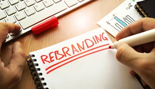 Rebranding Redesign your logo concept shown by a person writing “rebranding” in a notebook, representing planning and strategy for updating a brand identity and logo design.