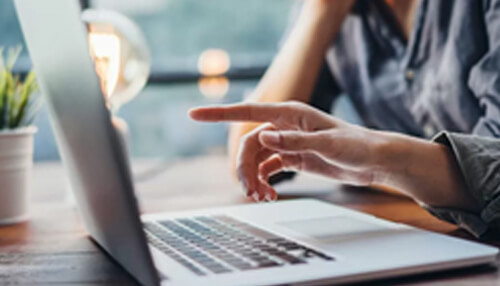 Person pointing at a laptop screen, researching how to get a mortgage with specialist mortgage broker advice. Get a mortgage