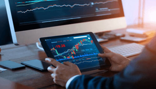 Forex in thailand Investor analyzing forex charts on computer and tablet screens, focused on forex in thailand market trends.