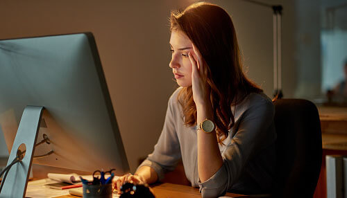 Employee working long hours in front of a computer, highlighting common misconceptions employers have about longer work hours improving productivity. Common misconceptions employers