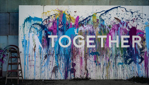 A picture of the word together painted onto a wall - tycoonstory | tycoonstory media Graffiti artwork by jerome karam in vibrant splashes of paint with the word'TOGETHER' across in bold white, to represent community.