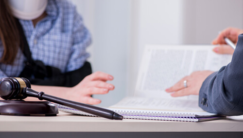 Worker’s compensation lawyer atlanta A compensation lawyer consultation with a client, having a gavel, notebook, and legal documents on the desk.
