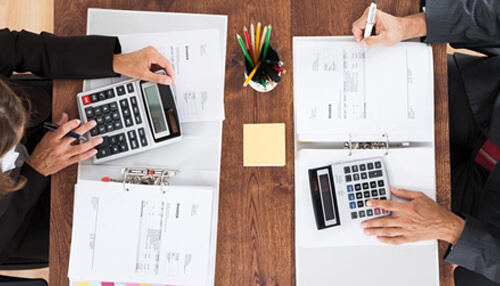 Determine a reasonable building size Two people holding calculators and looking over financial documents for starting a warehouse business.