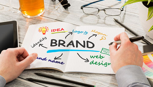 Develop and safeguard your brand Business owner brainstorming ideas for branding, logo, and web design to franchise their existing business, with a focus on brand identity.