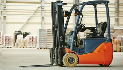 An indoor project would benefit from a stand up forklift A close-up view of a forklifts in a warehouse setting, ready to lift heavy loads, showcasing its functionality in material handling.