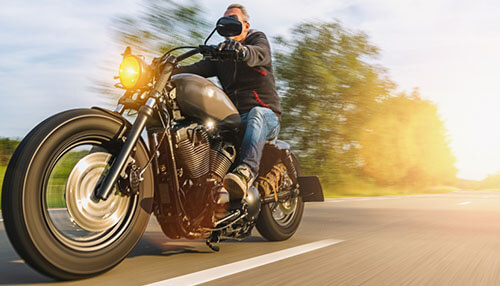 Riding a harley isn’t for everyone A sunset or sunrise view of an industrial area with numerous smokestacks emitting heavy smoke and pollution, alongside a network of power lines and electricity pylons.