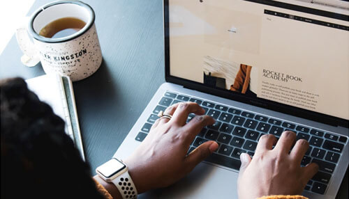 Include freelancers in your weekly meetings A close-up of a freelancers working on a laptop with a cup of coffee shows productivity at home.