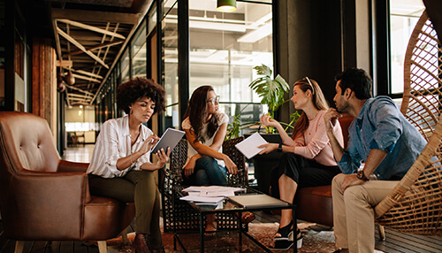 Lack of proper communication A group of people sitting and discussing in the office corridor symbolizes a lack of proper communication in between them.