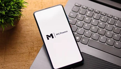 M1 finance mobile app Smartphone showing m1 finance app on laptop keyboard, ideal for m1 finance review article.
