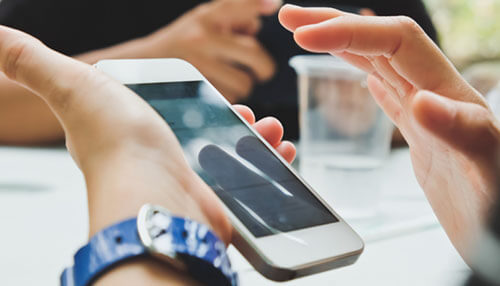 Mobile device plans - tycoonstory | tycoonstory media A person holding a smartphone during a conversation, representing cybersecurity strategies.