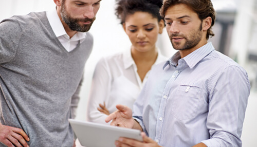 Online presence Team reviewing information on a tablet, discussing how a virtual assistant in small business can support daily operations and workflow management.