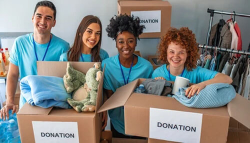 Research similar groups Volunteers holding donation boxes filled with clothes and toys, showcasing community support activities organized by a private foundation.