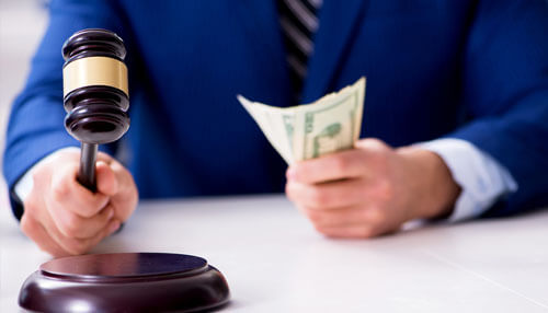 Workers’ compensation lawyer atlanta charge Workers compensation lawyer holding a gavel in one hand and cash in the other, symbolizing legal settlements or compensation.