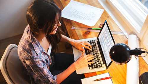 Blogger Online business ideas workspace with woman typing on laptop at wooden desk, planning digital startup strategy.