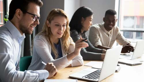 Successful business A diverse team of professionals collaborating in an office setting, working on laptops and discussing strategies for building a successful business.