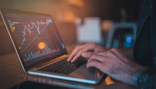 Savings in cryptocurrency Monitoring savings in cryptocurrency using trading charts on a laptop.