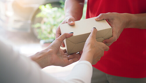 Close-up of hands exchanging a package, representing ecommerce fulfillment and the process of selling an online business Screen potential buyers for selling your ecommerce business