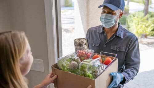 Delivery driver handing a box of fresh groceries to a customer at their doorstep, representing a delivery service business focused on food delivery Quality of service in a delivery service business