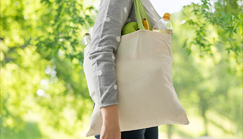 Person carrying reusable shopping bag filled with groceries, promoting eco-friendly and sustainable living Person carrying a reusable bag as part of sustainable lifestyle choices that inspire green business ideas.