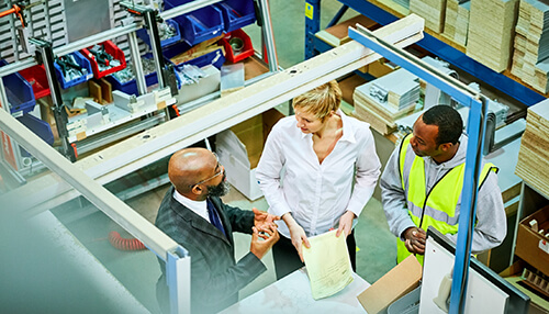 Production management team in a factory setting, discussing plans and strategies with a focus on collaboration and efficiency Role of the team production management