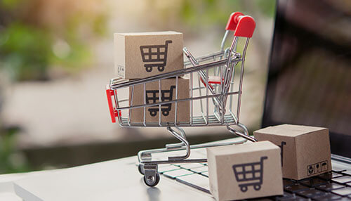 Sell on an online marketplace Miniature shopping cart with boxes on a laptop keyboard, symbolizing e-commerce as a way to make money online and offline through selling products