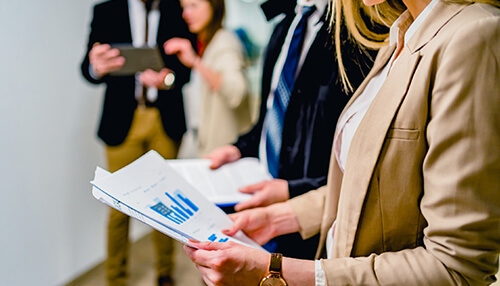 A group of business professionals reviewing reports and charts in a modern office setting, discussing collaboration strategies Study local business collaborate
