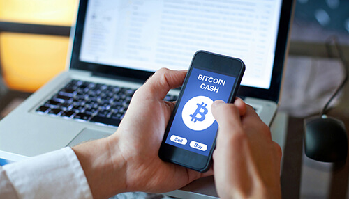 Understanding bitcoin cash Bitcoin cash mobile trading interface displayed on smartphone with buy and sell options in front of laptop screen.